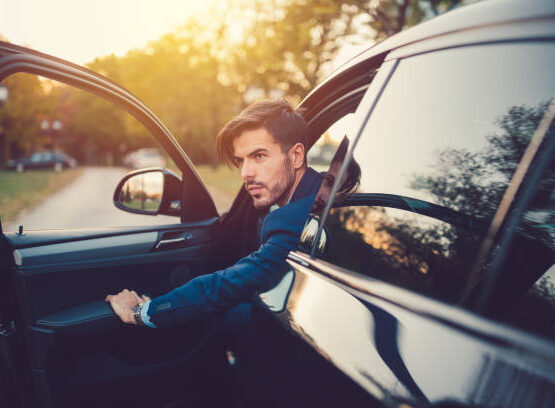 Young man in car looking at view through the open car door